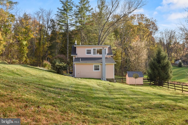 rear view of property featuring a storage shed and a lawn