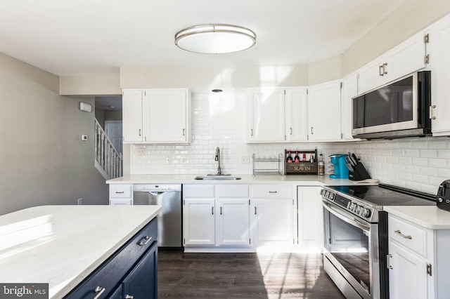 kitchen featuring sink, backsplash, white cabinets, and appliances with stainless steel finishes