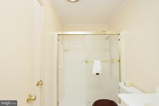 bathroom with a shower with door, crown molding, vanity, and toilet