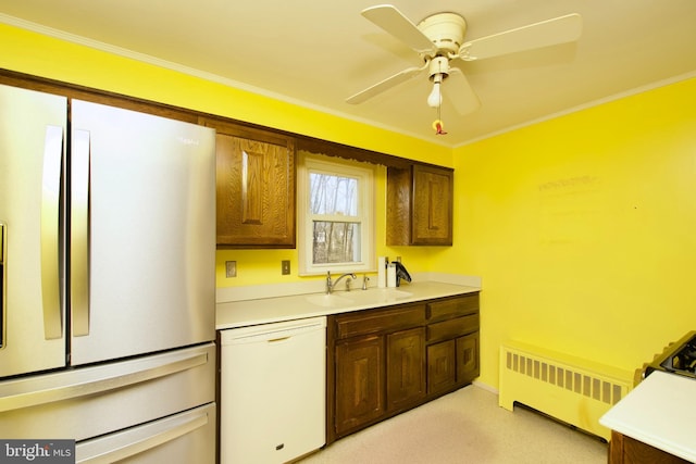 kitchen with radiator heating unit, refrigerator, sink, white dishwasher, and crown molding