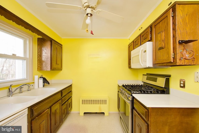 kitchen featuring radiator, sink, crown molding, ceiling fan, and gas stove