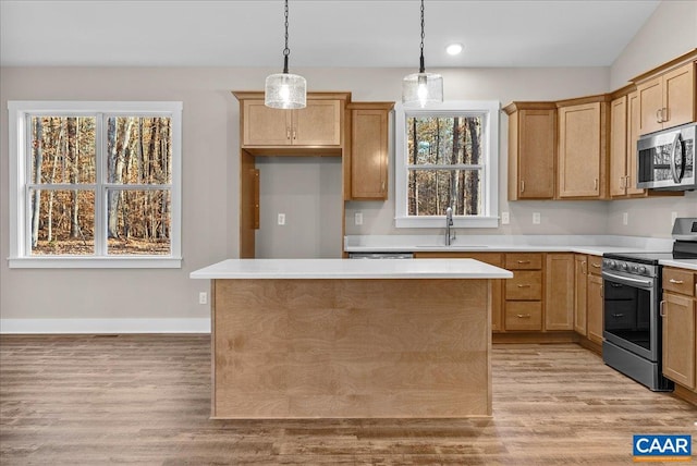 kitchen with stainless steel appliances, plenty of natural light, decorative light fixtures, a kitchen island, and sink