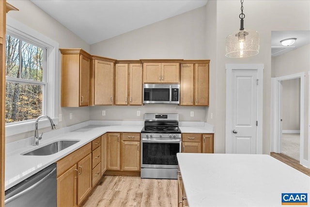 kitchen featuring stainless steel appliances, hanging light fixtures, vaulted ceiling, light hardwood / wood-style flooring, and sink