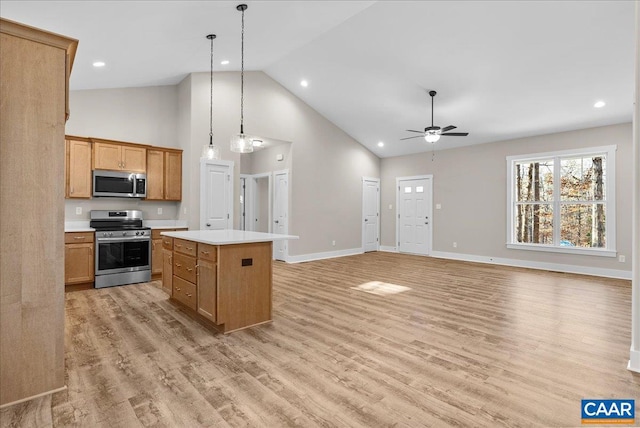 kitchen featuring decorative light fixtures, ceiling fan, a center island, stainless steel appliances, and high vaulted ceiling