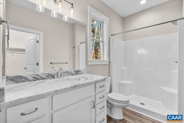 bathroom with toilet, vanity, wood-type flooring, and walk in shower