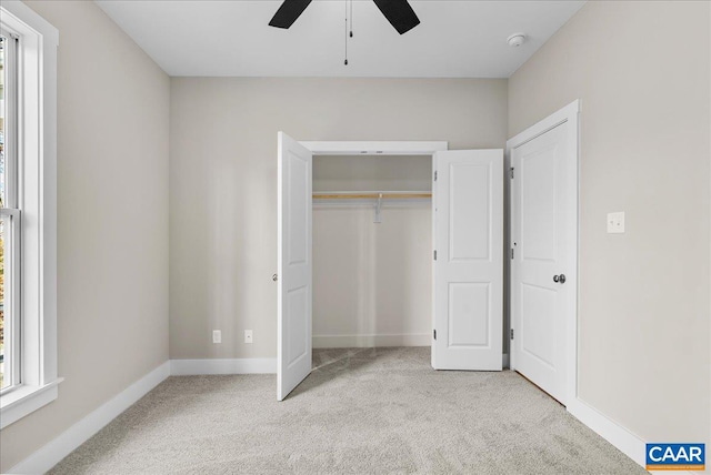 unfurnished bedroom featuring ceiling fan, a closet, and light colored carpet