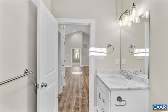 bathroom featuring hardwood / wood-style flooring, vanity, and lofted ceiling