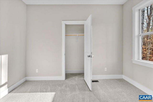 unfurnished bedroom featuring light colored carpet, a closet, and multiple windows