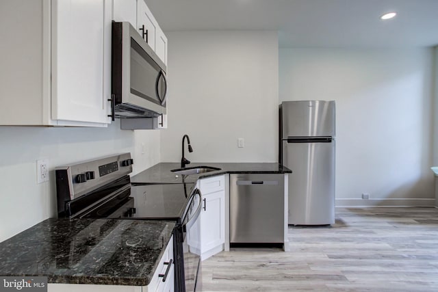 kitchen featuring white cabinets, appliances with stainless steel finishes, sink, and dark stone counters