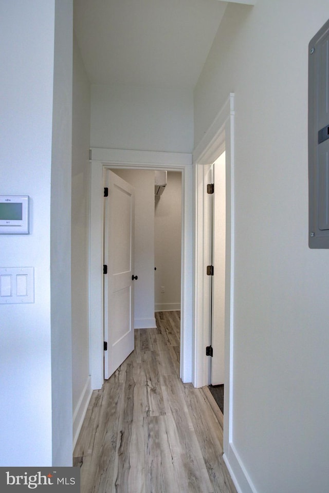 corridor with light wood-type flooring and electric panel