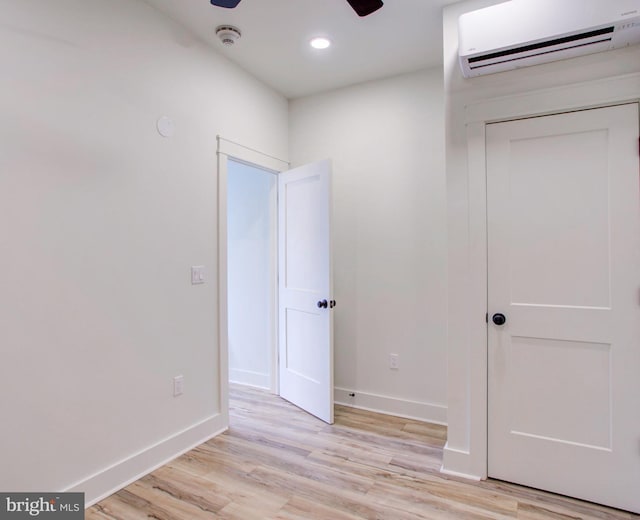 unfurnished room featuring light wood-type flooring and a wall mounted air conditioner