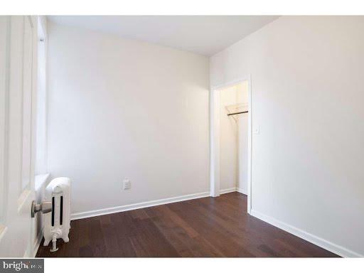 unfurnished room featuring radiator heating unit and dark hardwood / wood-style flooring