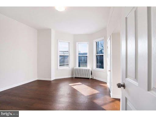 unfurnished room featuring dark hardwood / wood-style floors and radiator