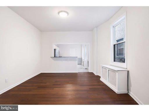 unfurnished room featuring radiator and dark hardwood / wood-style flooring