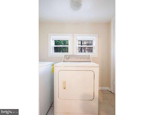 clothes washing area with light tile patterned flooring and washing machine and dryer