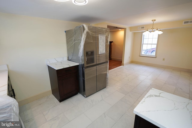 kitchen with dark brown cabinetry, light stone counters, baseboards, and visible vents