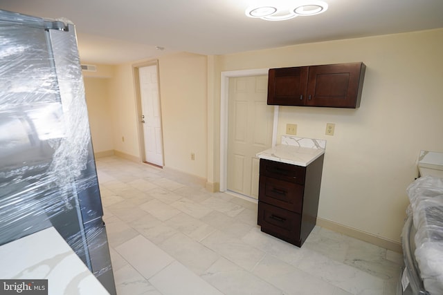 interior space with dark brown cabinets, marble finish floor, and light countertops