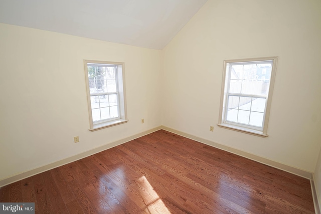 empty room featuring baseboards, lofted ceiling, and wood finished floors