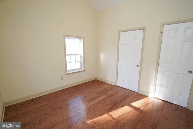 unfurnished bedroom with high vaulted ceiling and hardwood / wood-style floors