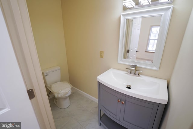 bathroom featuring toilet, vanity, and baseboards