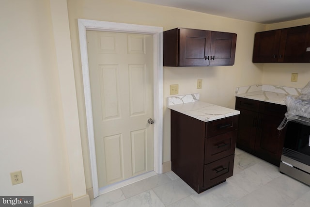 kitchen with electric range, dark brown cabinets, marble finish floor, and light stone counters