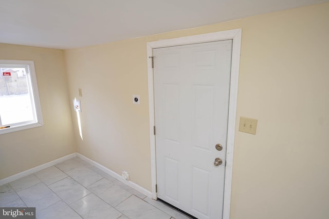 doorway with baseboards and marble finish floor