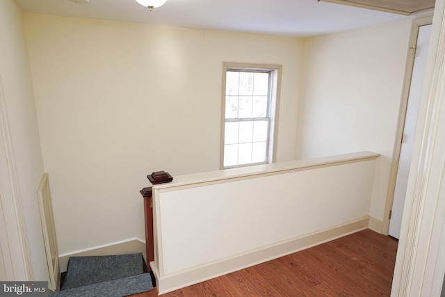 staircase featuring wood finished floors and baseboards