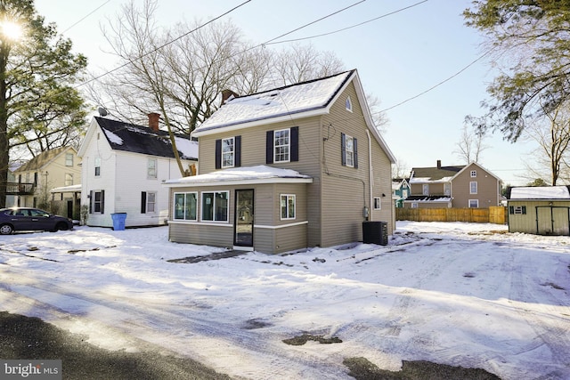 view of front of house featuring a shed, a chimney, an outdoor structure, and fence