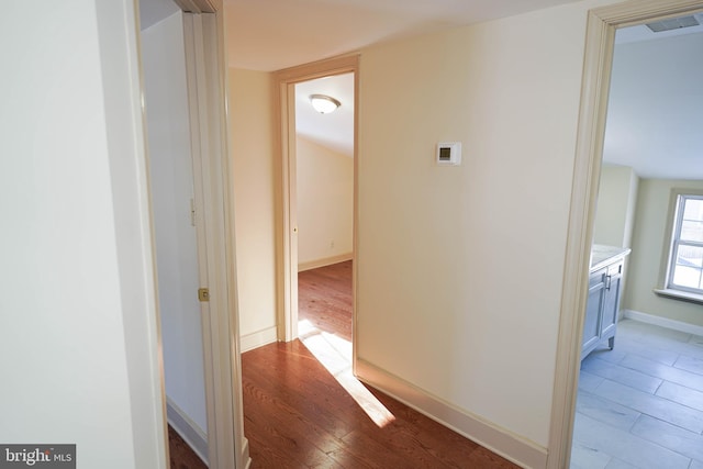 hallway featuring visible vents, baseboards, and light wood-style floors