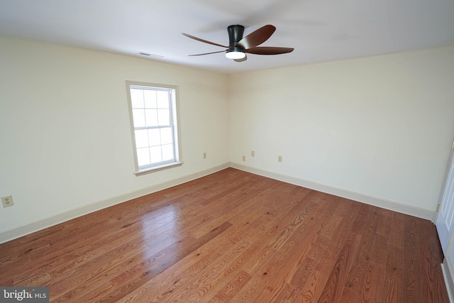 spare room featuring visible vents, baseboards, wood finished floors, and a ceiling fan