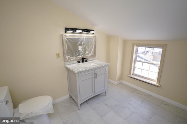 bathroom featuring toilet, vanity, and vaulted ceiling