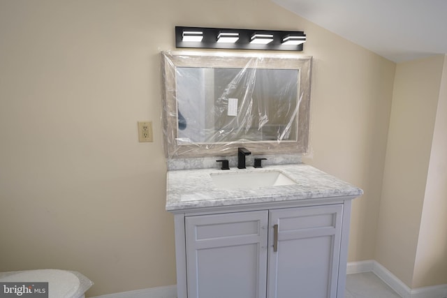 bathroom featuring baseboards, lofted ceiling, and vanity