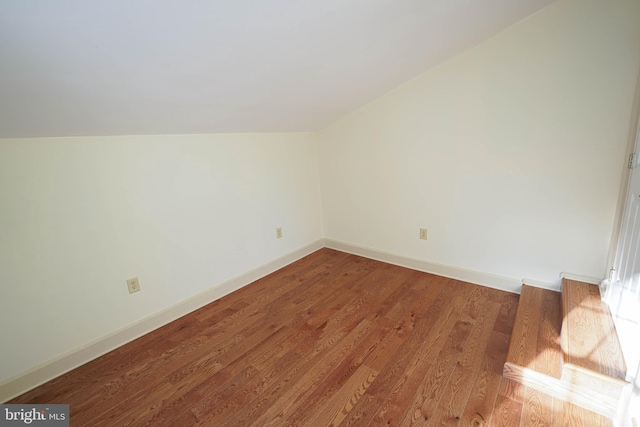 additional living space with wood-type flooring and vaulted ceiling