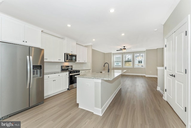 kitchen with ceiling fan, appliances with stainless steel finishes, white cabinetry, and an island with sink