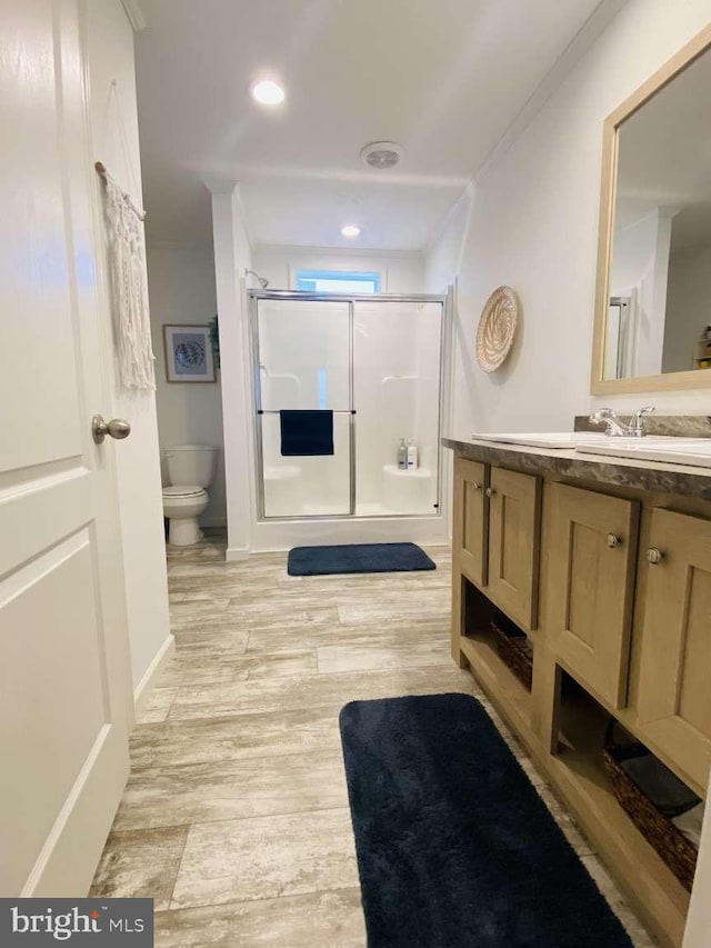 bathroom featuring toilet, vanity, wood-type flooring, crown molding, and an enclosed shower