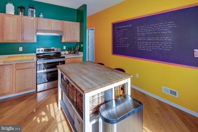 kitchen with light brown cabinetry, electric stove, a kitchen island, and light hardwood / wood-style floors