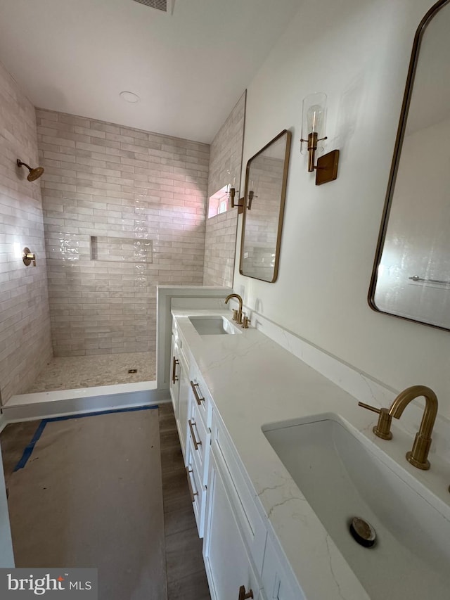 bathroom with a tile shower, vanity, and hardwood / wood-style flooring