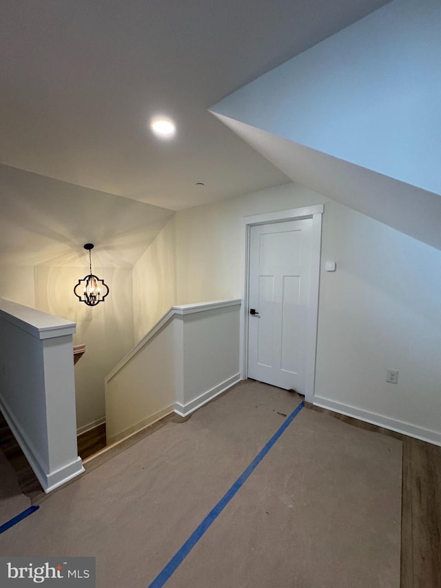 bonus room with an inviting chandelier, vaulted ceiling, and concrete floors