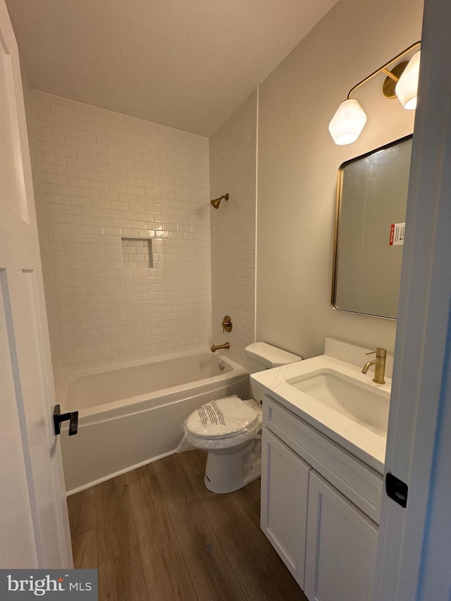 full bathroom featuring vanity, wood-type flooring, toilet, and tiled shower / bath