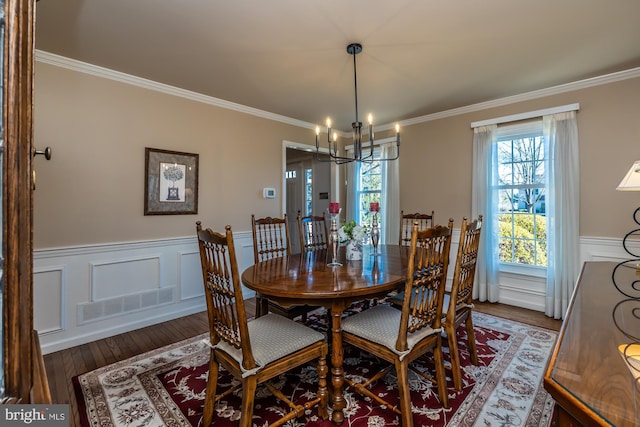 dining room featuring crown molding, a healthy amount of sunlight, dark wood-type flooring, and an inviting chandelier