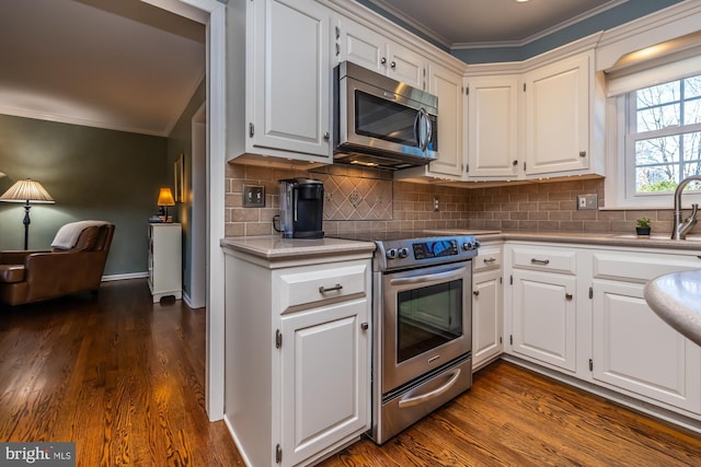 kitchen featuring sink, stainless steel appliances, ornamental molding, white cabinets, and dark hardwood / wood-style flooring