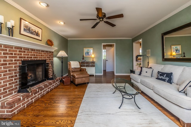 living room with a brick fireplace, dark wood-type flooring, ornamental molding, and ceiling fan