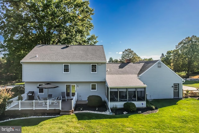 rear view of property featuring a wooden deck, a sunroom, and a lawn