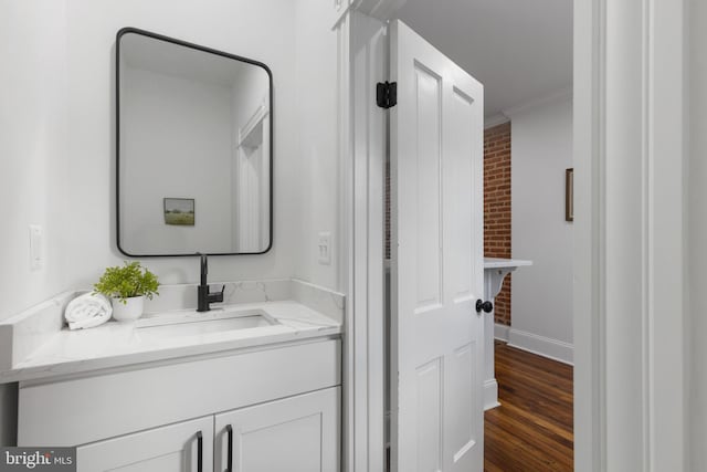 laundry area with brick wall, dark wood-type flooring, sink, and ornamental molding