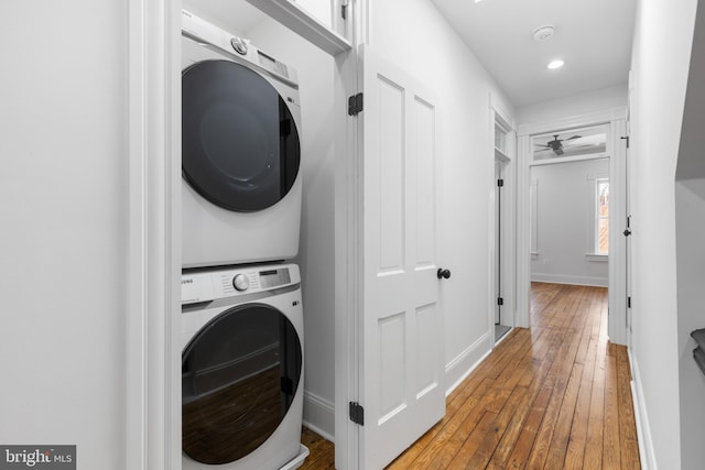 laundry area with stacked washing maching and dryer and hardwood / wood-style floors