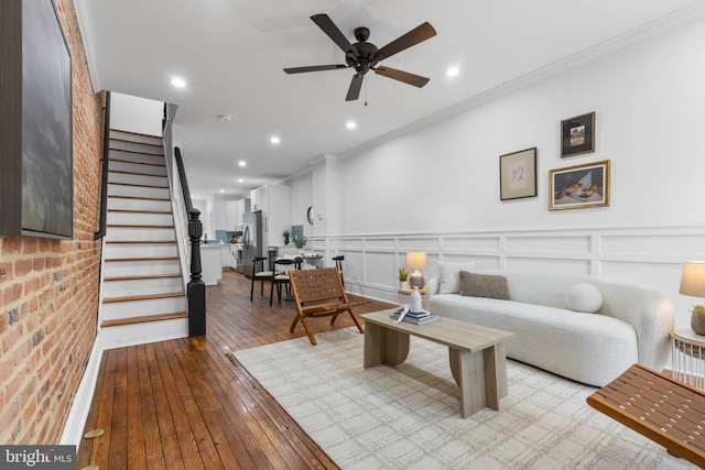 living room featuring ceiling fan, ornamental molding, and light wood-type flooring