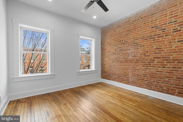 spare room featuring ceiling fan, brick wall, and hardwood / wood-style flooring