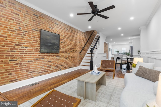 living room with ceiling fan, brick wall, and crown molding