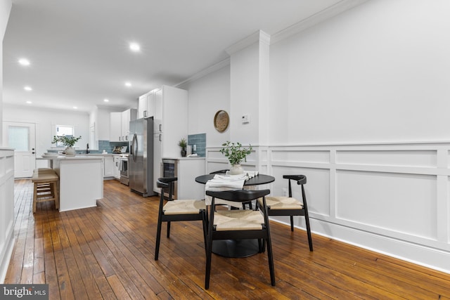 dining space featuring sink, beverage cooler, dark hardwood / wood-style floors, and ornamental molding