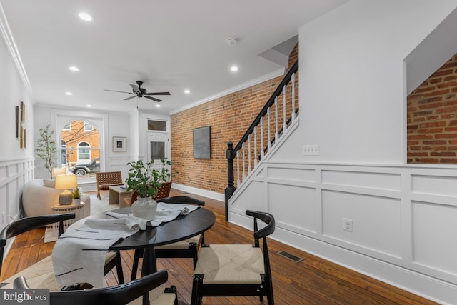 dining room with ceiling fan, brick wall, crown molding, and hardwood / wood-style floors